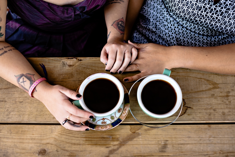 A same sex couple hold hands and drink coffee in brooklyn, ny.